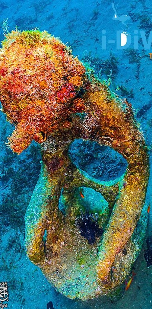 Underwater sculpture covered in orange coral in Dahab